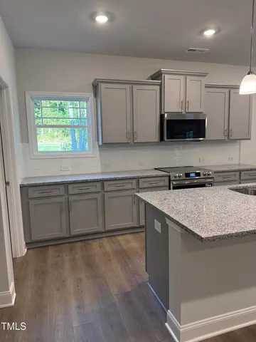 a kitchen with granite countertop a stove a sink and a microwave