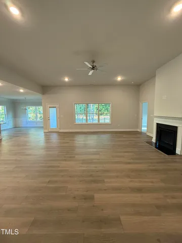 a view of an empty room with window and a kitchen