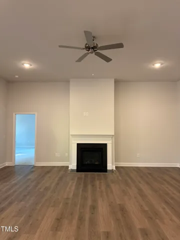an empty room with fireplace and a ceiling fan