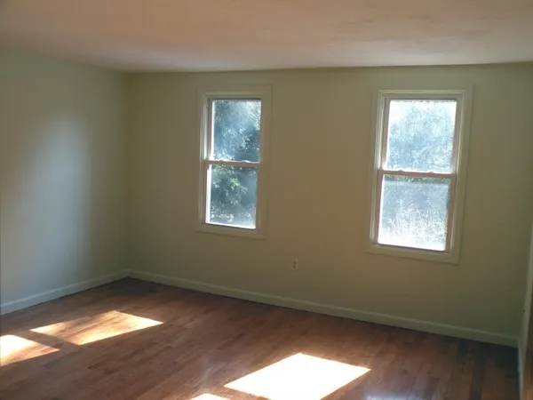 an empty room with wooden floor and closet area
