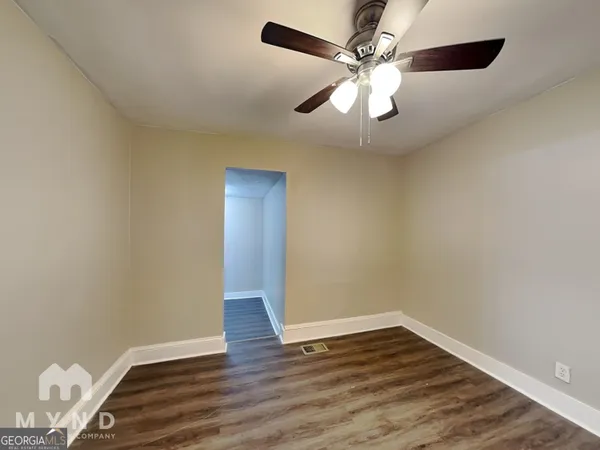 a view of an empty room with window and wooden floor