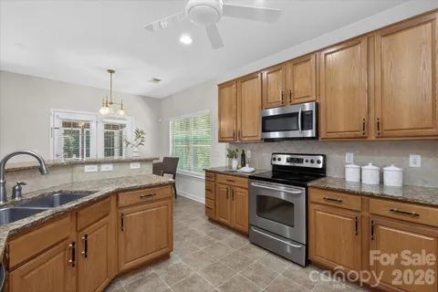 a kitchen with stainless steel appliances granite countertop a stove sink microwave and window