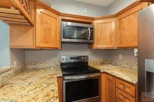 a kitchen with stainless steel appliances granite countertop white cabinets and a stove top oven