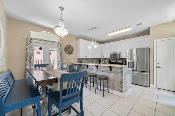 a kitchen with stainless steel appliances granite countertop a stove top oven a sink a dining table and chairs with wooden floor