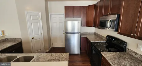 a kitchen with a refrigerator stove and wooden cabinets