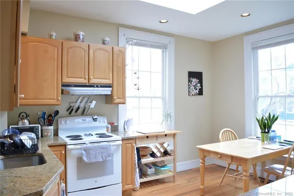 a kitchen with stainless steel appliances granite countertop a stove a sink dishwasher and cabinets with wooden floor