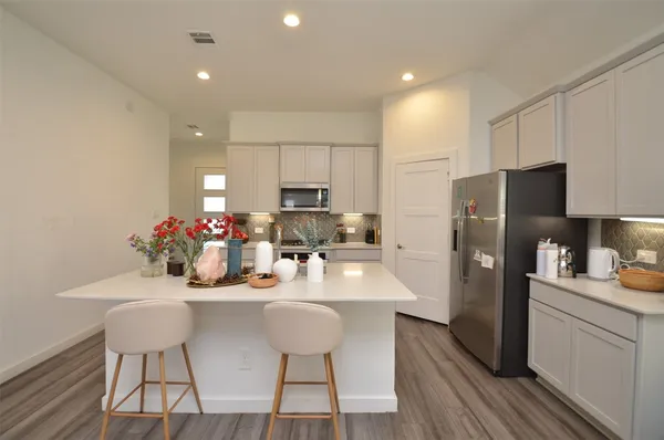 a kitchen with refrigerator a microwave oven a sink and chairs with wooden floor