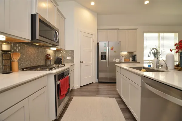a kitchen with stainless steel appliances granite countertop a stove a sink and a refrigerator