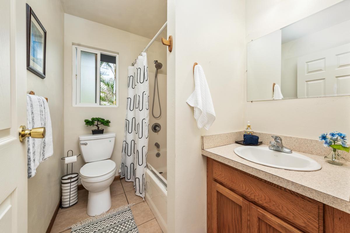 92-8583 Paradise Parkway Ocean View, HI 96704 - Photo 11 of 28 a bathroom with a sink a toilet and shower curtain