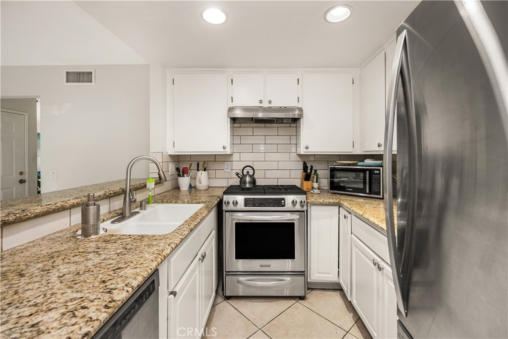 5573 East Vista Del Rio Anaheim, CA 92807 - Photo 17 of 42 a kitchen with stainless steel appliances granite countertop a sink stove and refrigerator
