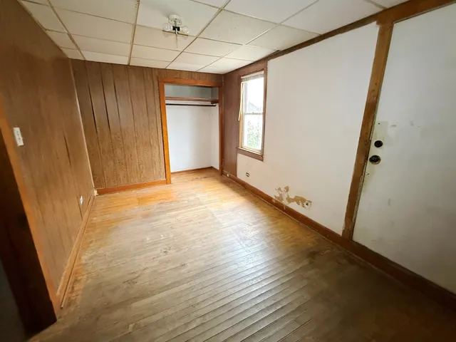 an empty room with wooden floor and windows with curtains