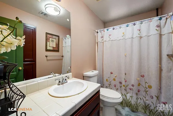 a bathroom with a sink a toilet and shower curtain