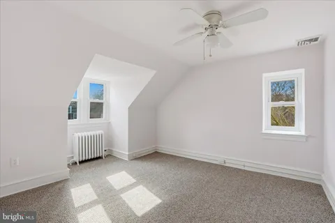 an empty room with windows and ceiling fan