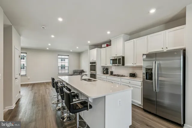 a kitchen with stainless steel appliances a refrigerator a stove a sink a dining table and chairs