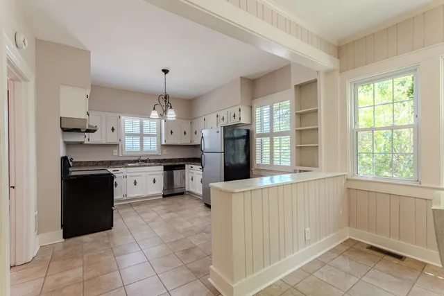 a kitchen with stainless steel appliances granite countertop a refrigerator a sink dishwasher a stove and white cabinets