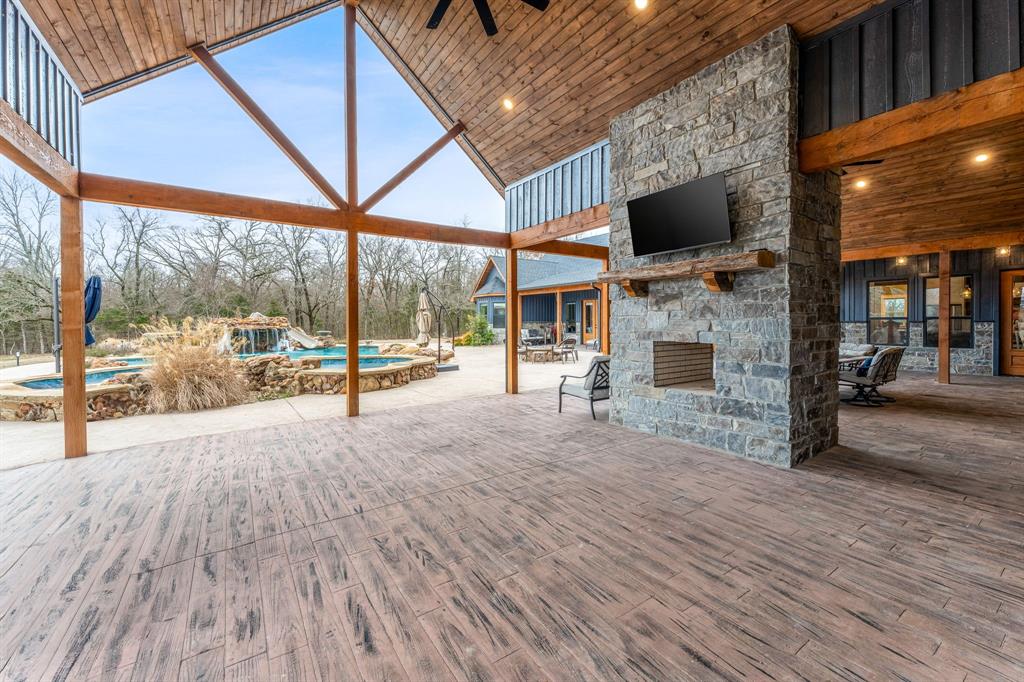 239 32507th Road Paris, TX 75460 - Photo 32 of 40 View of patio / terrace with an outdoor stone fireplace, an outdoor pool, ceiling fan, and outdoor dining area
