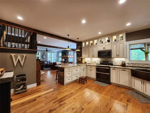 a kitchen with stainless steel appliances granite countertop a stove top oven a sink dishwasher a dining table and chairs with wooden floor