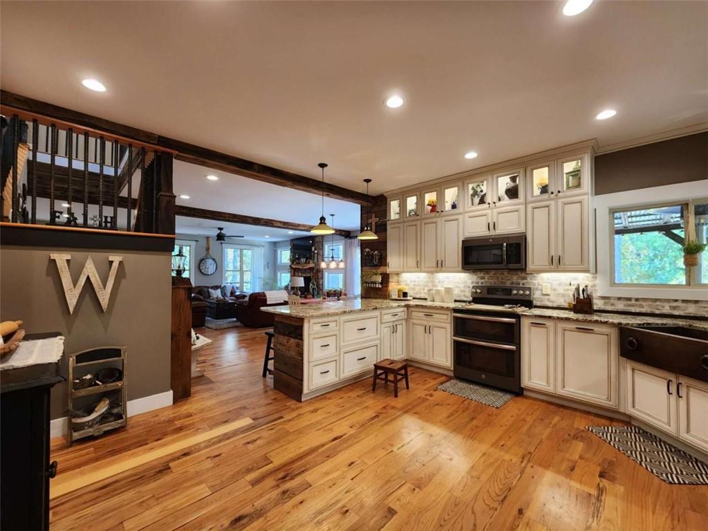 7350 Banks Mill Road Douglasville, GA 30135 - Photo 6 of 27 a kitchen with stainless steel appliances granite countertop a stove top oven a sink dishwasher a dining table and chairs with wooden floor