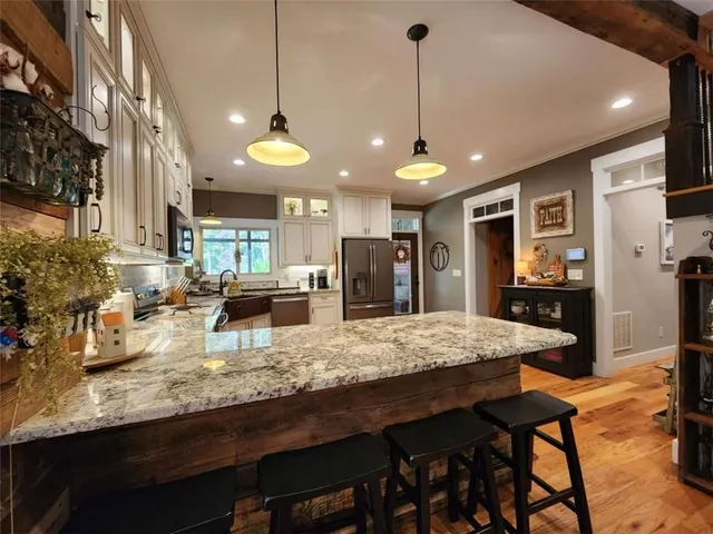 a kitchen with stainless steel appliances granite countertop a stove a refrigerator a oven a sink with island and chairs