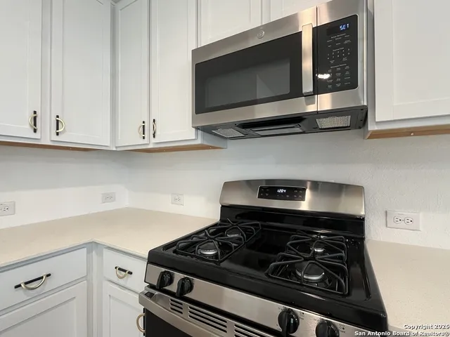 a kitchen with stainless steel appliances granite countertop white cabinets and a stove top oven with granite countertops