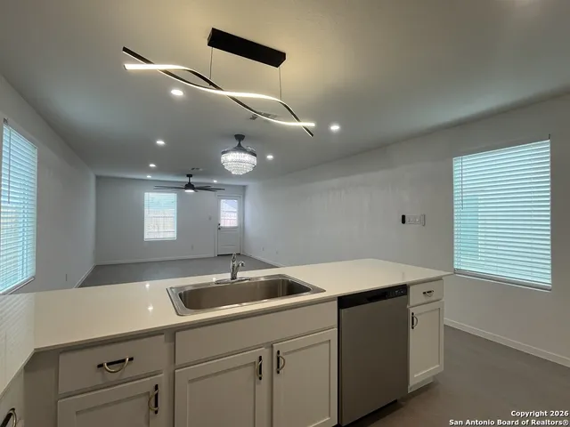 a kitchen with a sink dishwasher and white cabinets with wooden floor
