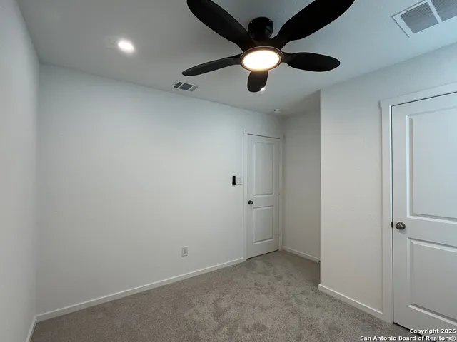 an empty room with a ceiling fan and window