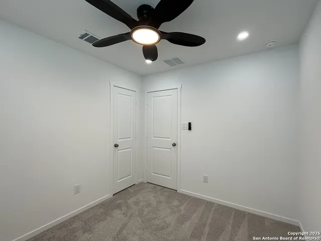 an empty room with a ceiling fan and a window