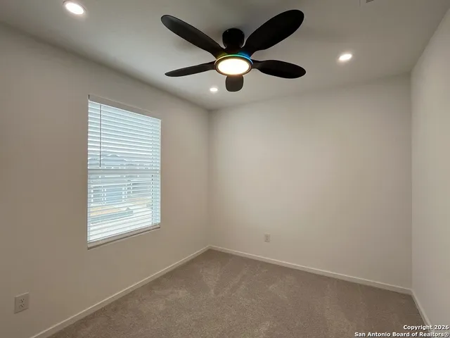 an empty room with a window and a fan