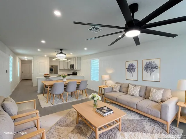 a living room with lots of furniture and a ceiling fan
