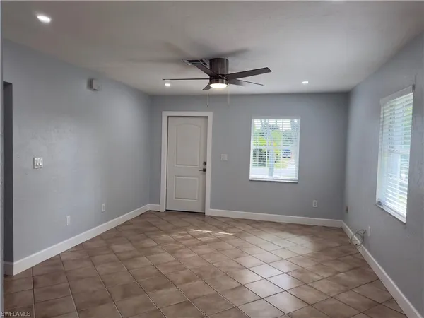 an empty room with windows and fan
