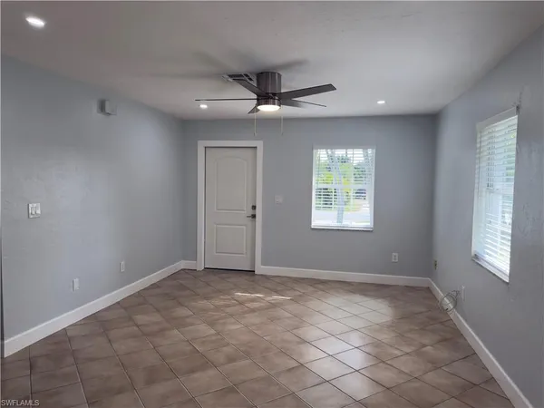 an empty room with windows and chandelier fan
