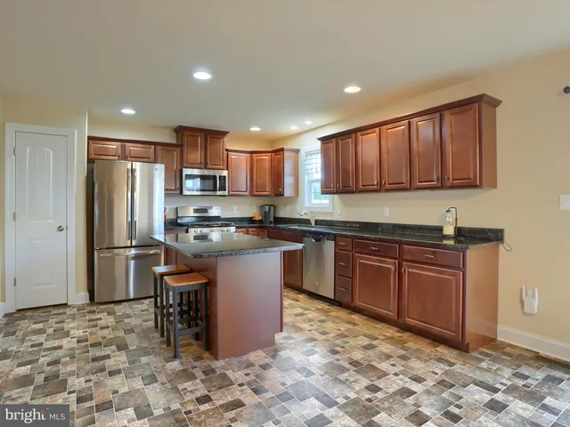 a kitchen with granite countertop wooden cabinets a refrigerator and a stove top oven