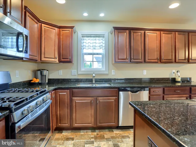 a kitchen with stainless steel appliances granite countertop a stove a sink and a microwave