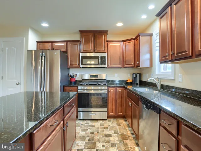 a kitchen with stainless steel appliances granite countertop a refrigerator a sink a stove a microwave and cabinets