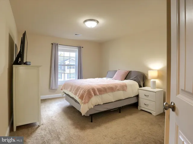 a spacious bedroom with a bed and a refrigerator