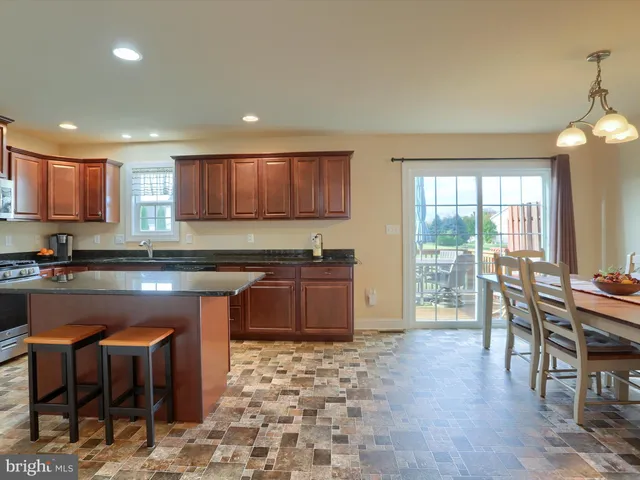 a kitchen with granite countertop a stove a sink a dining table and chairs