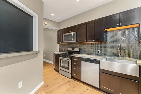 a kitchen with stainless steel appliances granite countertop a stove a sink and a microwave