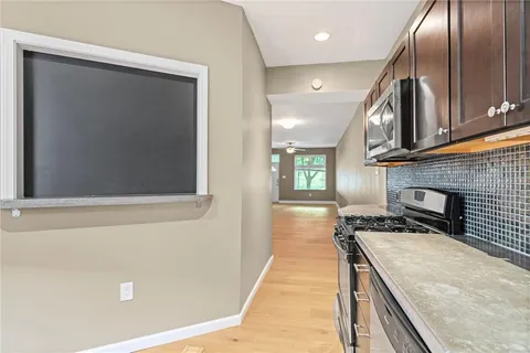 a kitchen with stainless steel appliances granite countertop a refrigerator a stove and a sink with wooden floor