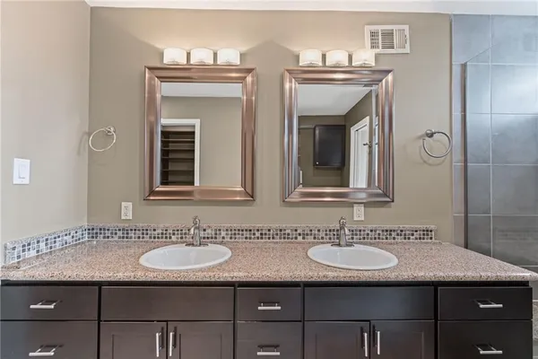 a bathroom with a granite countertop sink a mirror and a shower