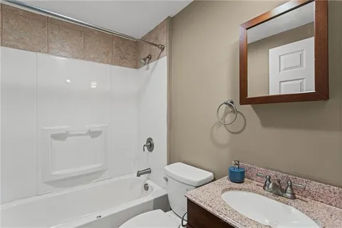 a bathroom with a granite countertop sink a toilet and shower