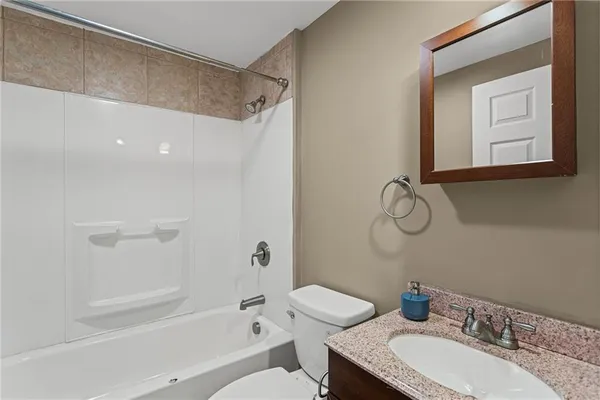a bathroom with a granite countertop sink a toilet and shower