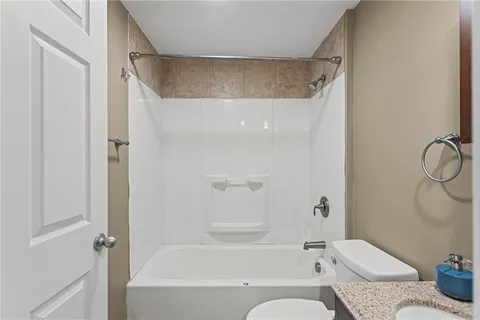 a bathroom with a granite countertop bathtub shower and toilet