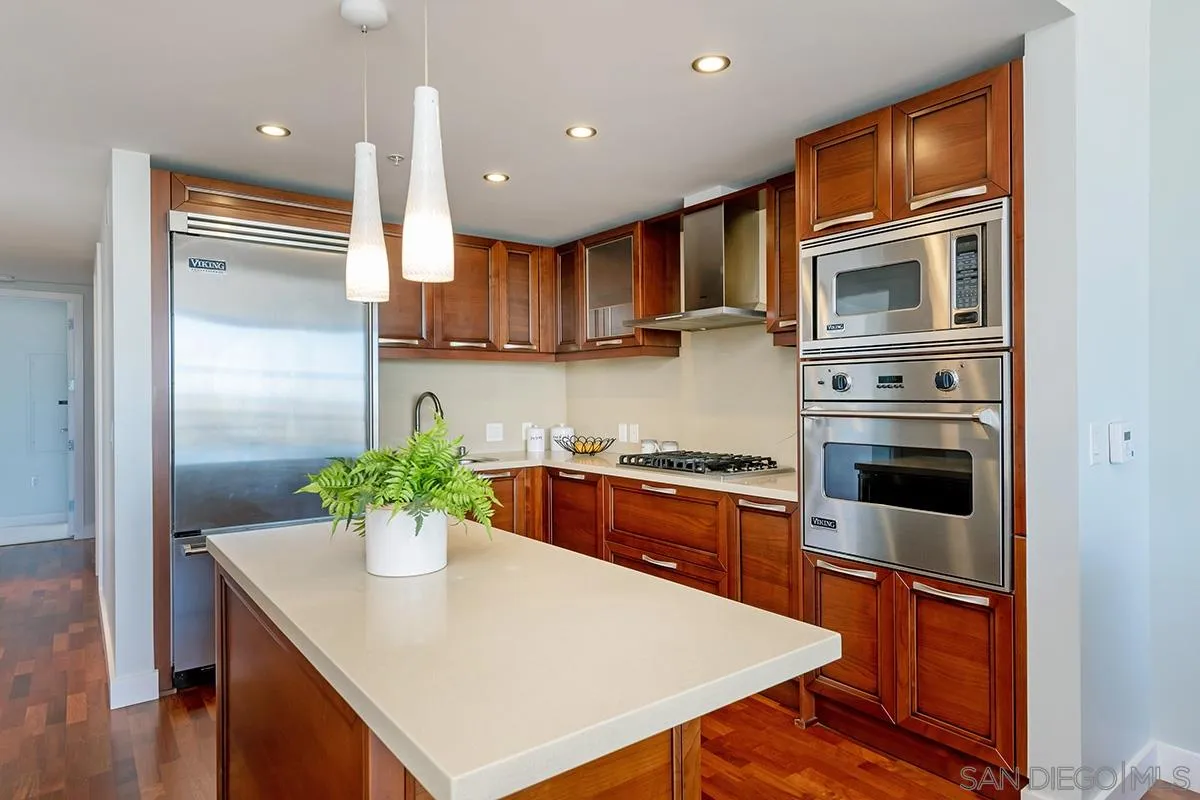 1325 Pacific Highway, Unit 2705 San Diego, CA 92101 - Photo 18 of 59 a kitchen with stainless steel appliances kitchen island granite countertop a refrigerator a stove and a sink with wooden floor