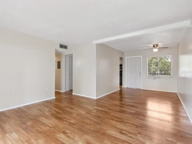 a view of an empty room with wooden floor and a window