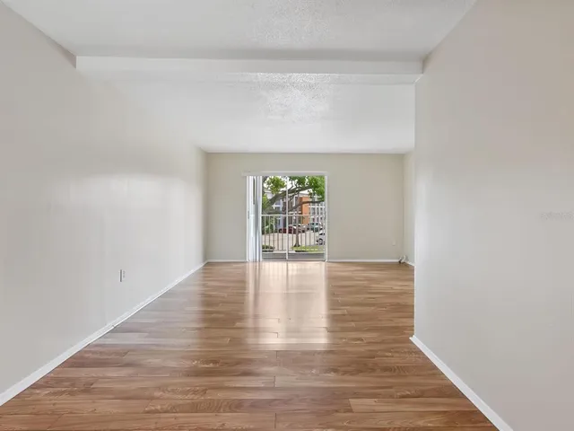 a view of an empty room with window and wooden floor