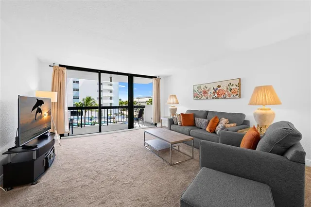 a living room with furniture a flat screen tv and a floor to ceiling window