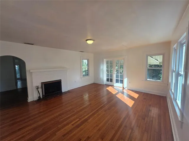 an empty room with windows a fireplace and wooden floor