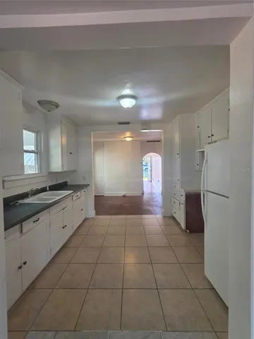 a large white kitchen with a sink and refrigerator