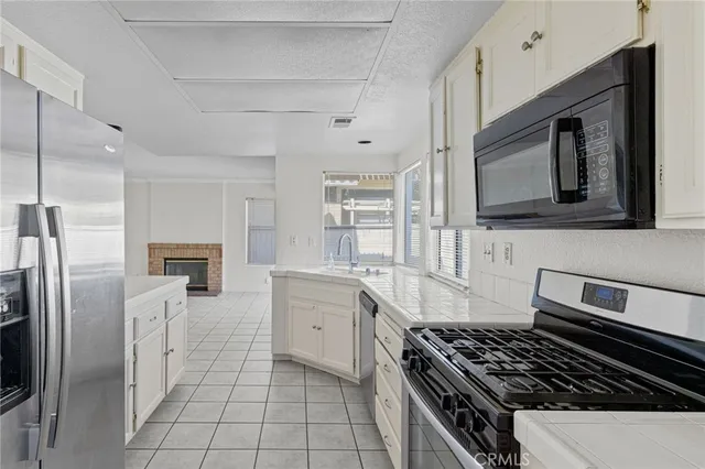 a kitchen with white cabinets appliances a sink and a window