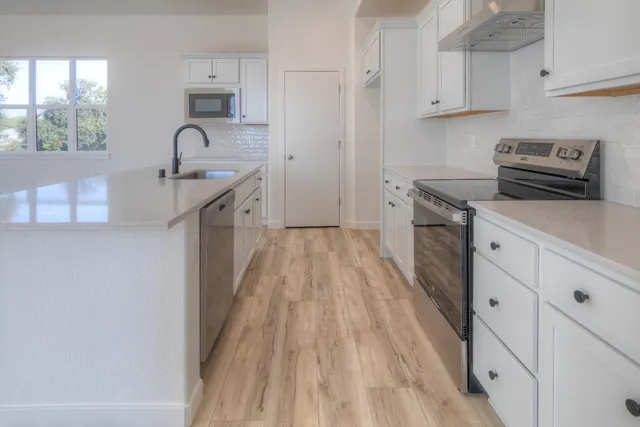 a kitchen with granite countertop a sink stove and cabinets